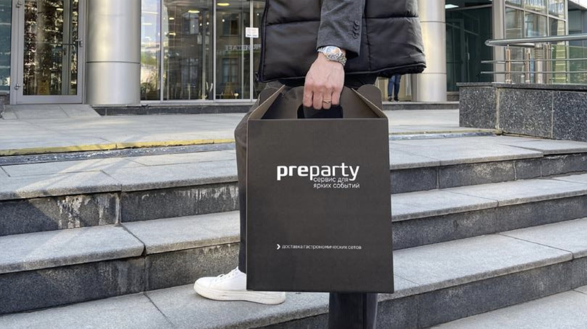 Курьер Preparty с фирменной упаковкой доставляет заказ к зданию