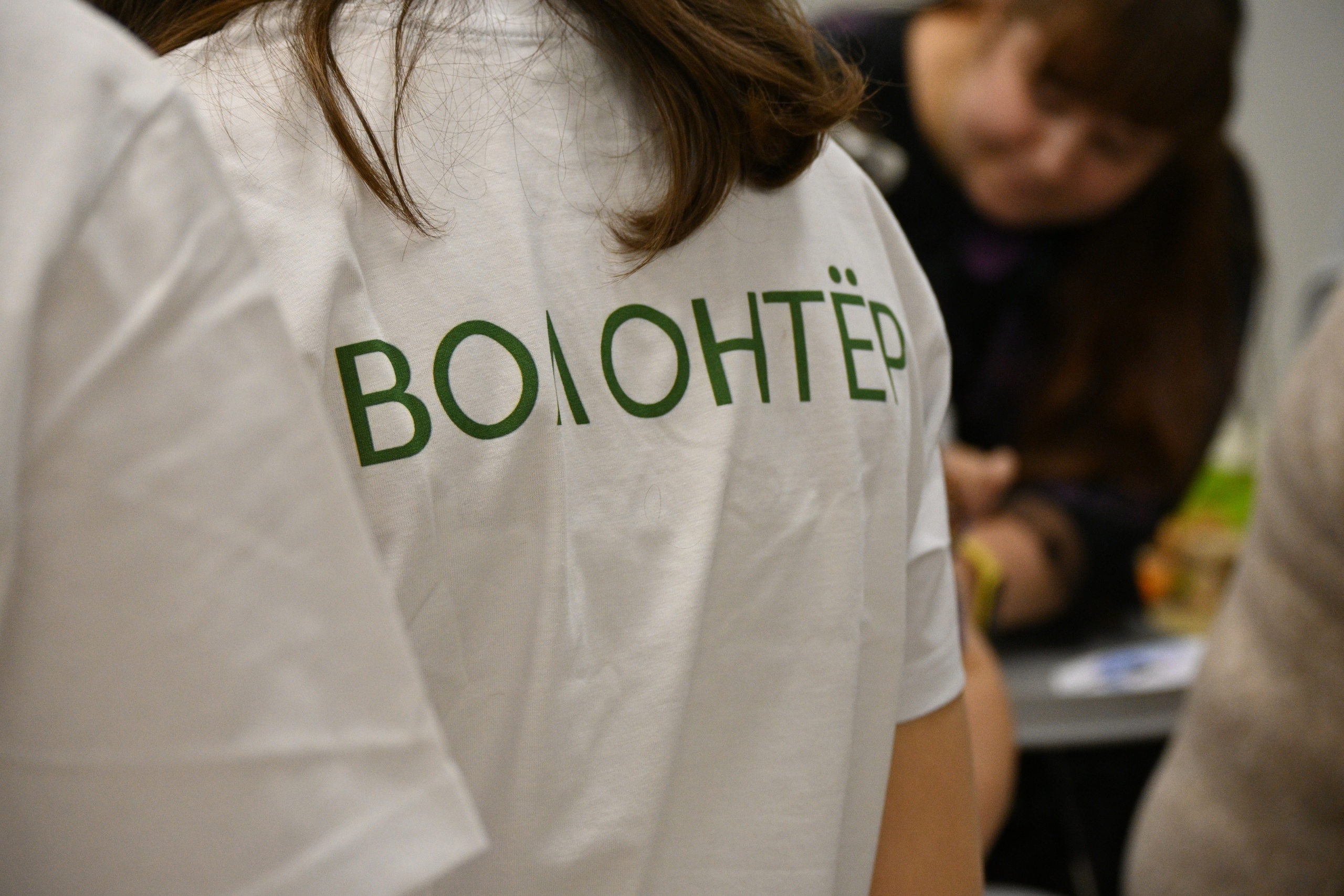 Волонтер в фирменной футболке с надписью (крупным планом)