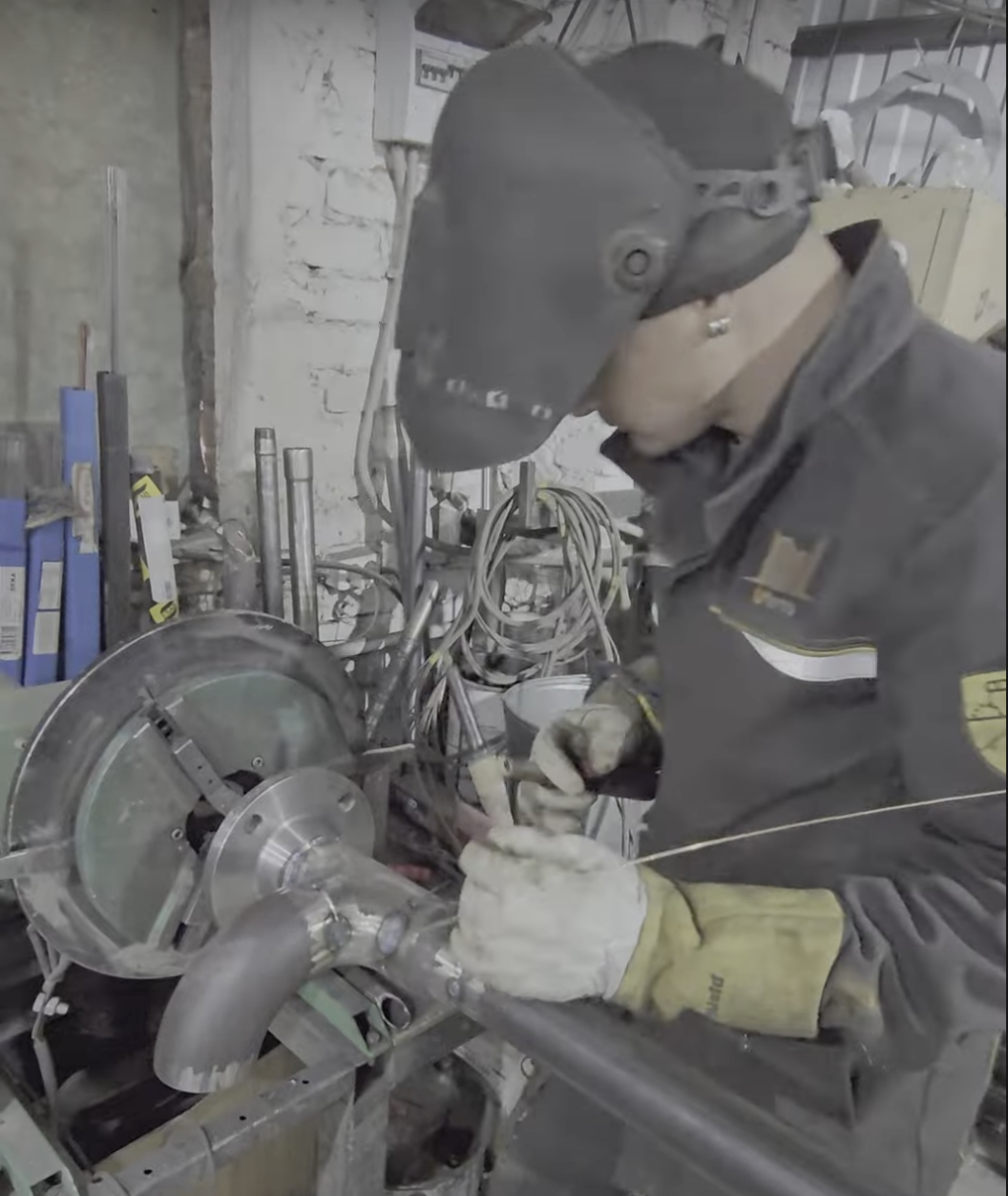 Рабочий в сварочной маске за сварочными процессами