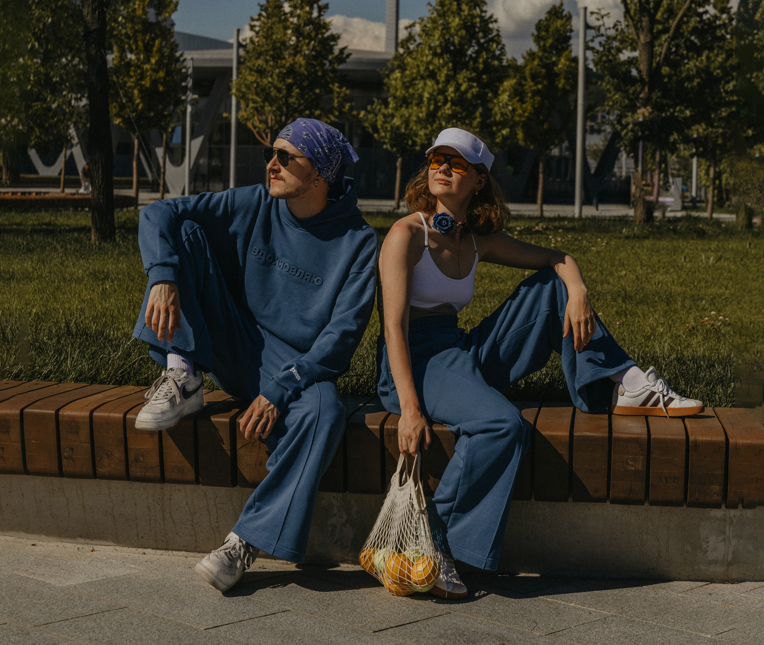 Модели в синих спортивных костюмах из коллекции «Свобода» от «Первой» позируют на скамейке в парке