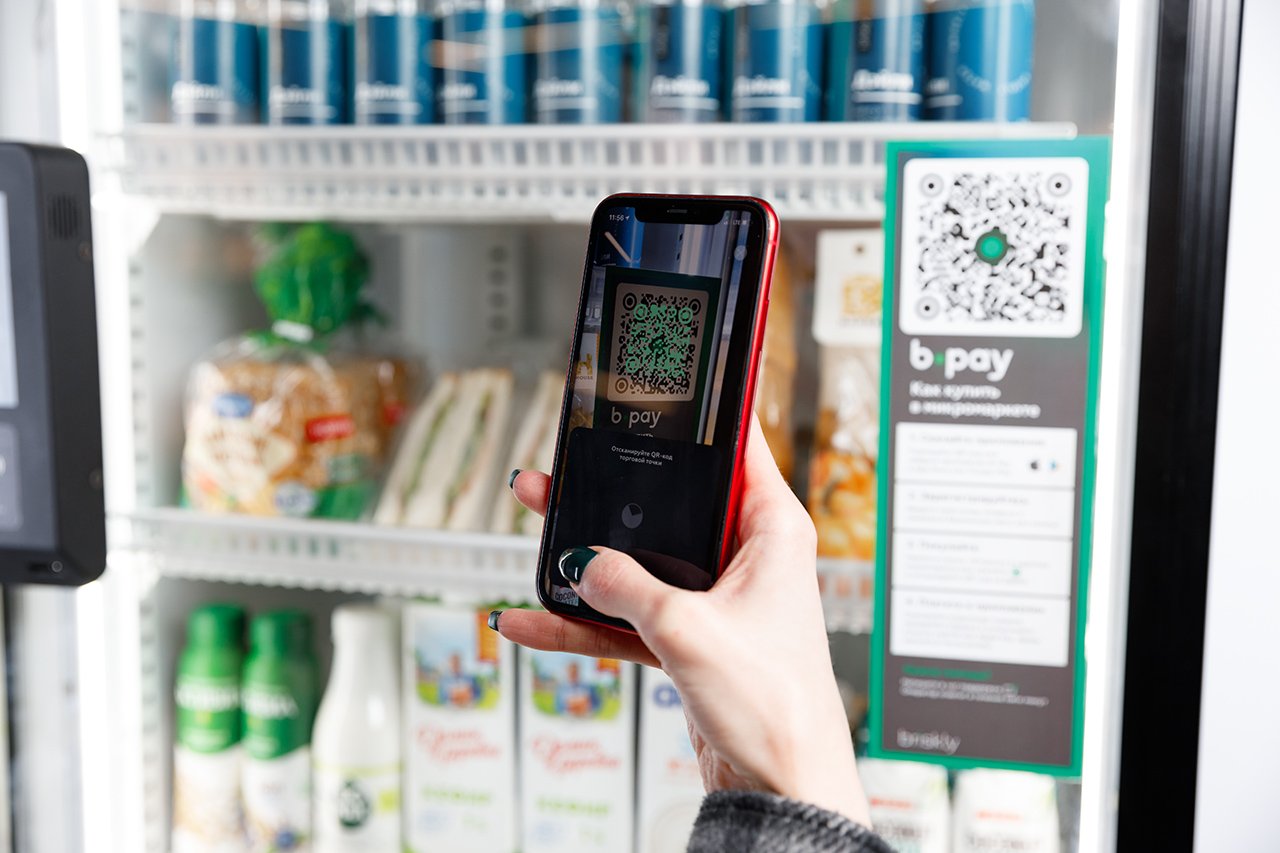 Покупатель выбирает товары в микромаркете с удобной системой самообслуживания, оплачивая покупку через мобильное приложение
