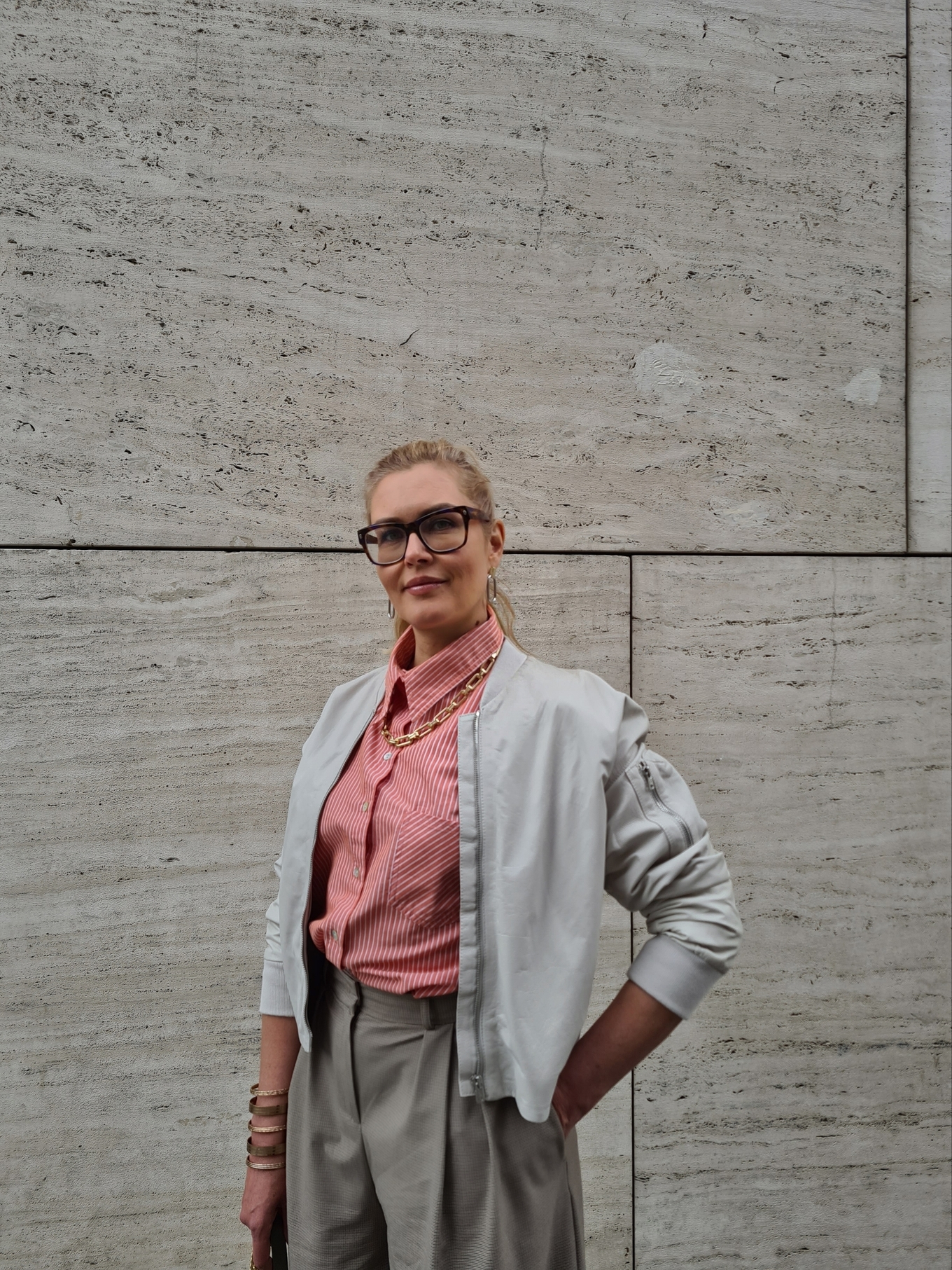 Девушка в полосатой рубашке стоит на фоне стены