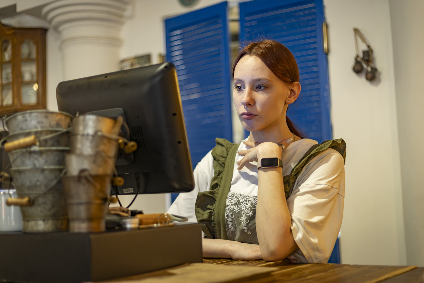 Девушка-официант в заведении Villa Karjala, задумчиво смотрит в POS-моноблок