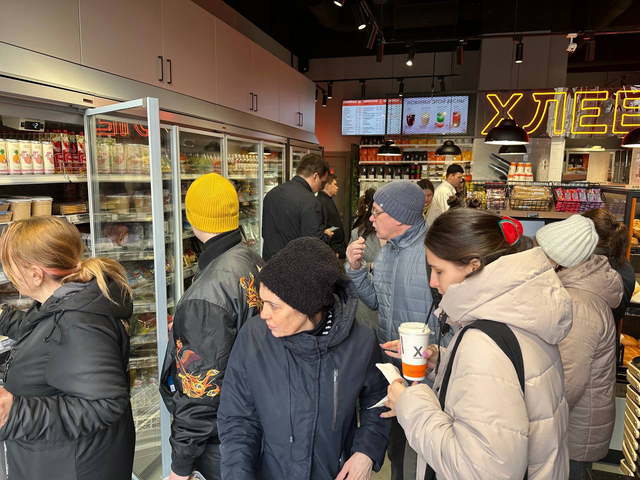 Витрина с охлажденными продуктами и посетители в магазине формата самообслуживания