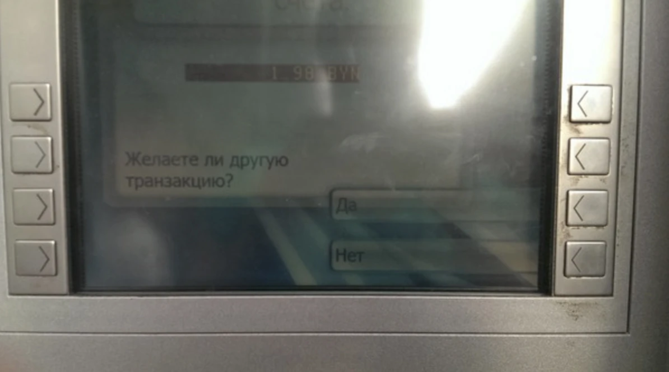 Экран банкомата с вопросом «Желаете ли другую транзакцию?» и вариантами ответа «Да» и «Нет», с бликами и отражениями на поверхности