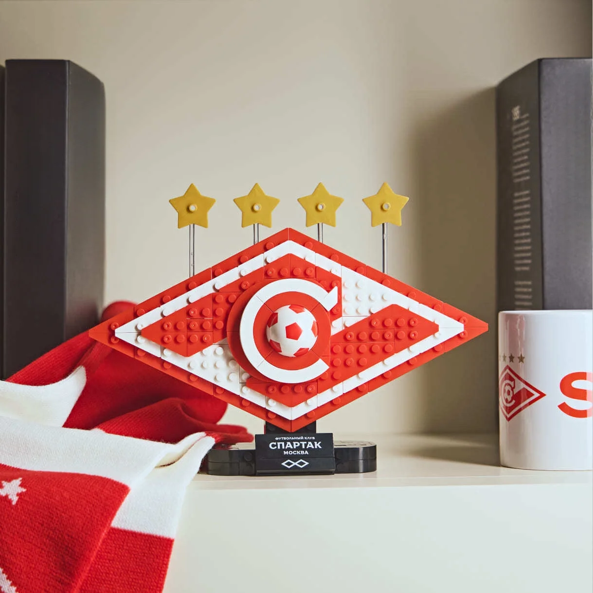 Собранная из конструктора эмблема футбольного клуба «Спартак» стоит на полке рядом с фанатским шарфом и кружкой