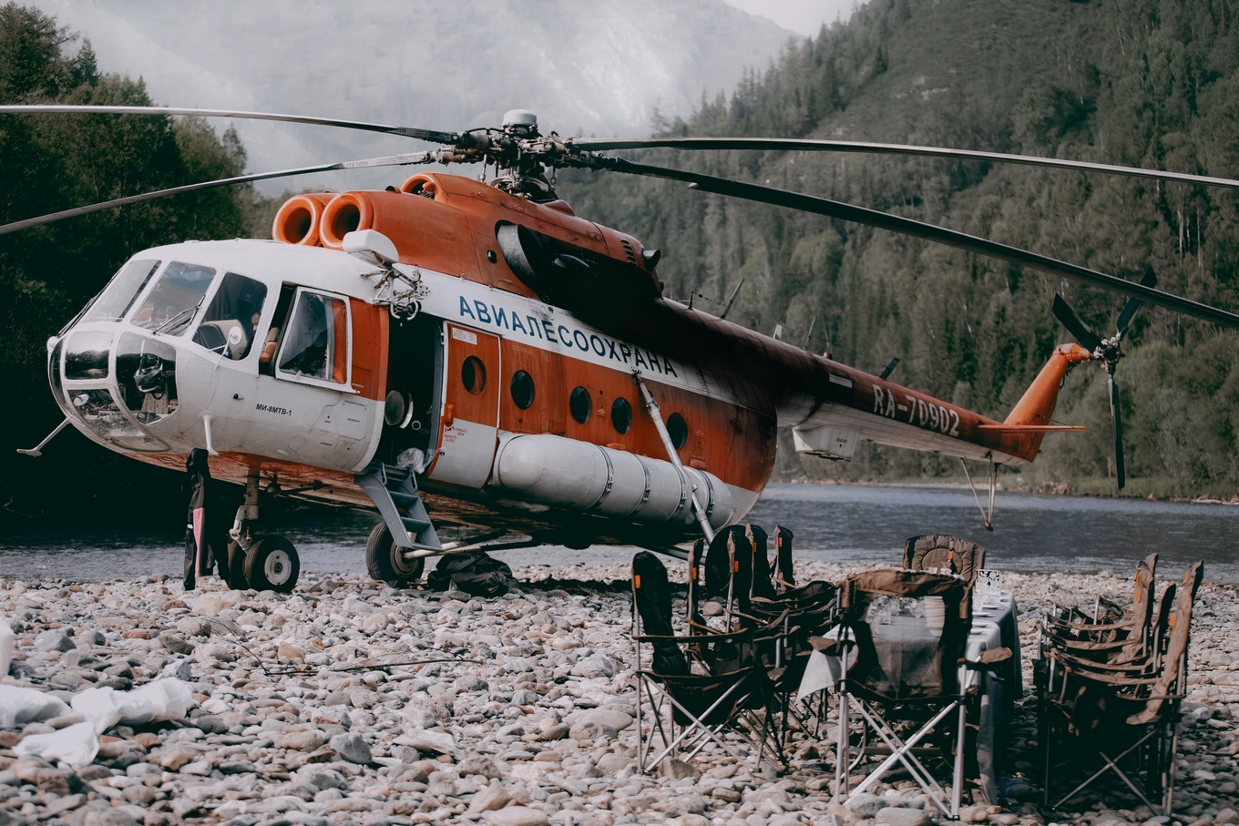 Обеденный стол на берегу реки и вертолет