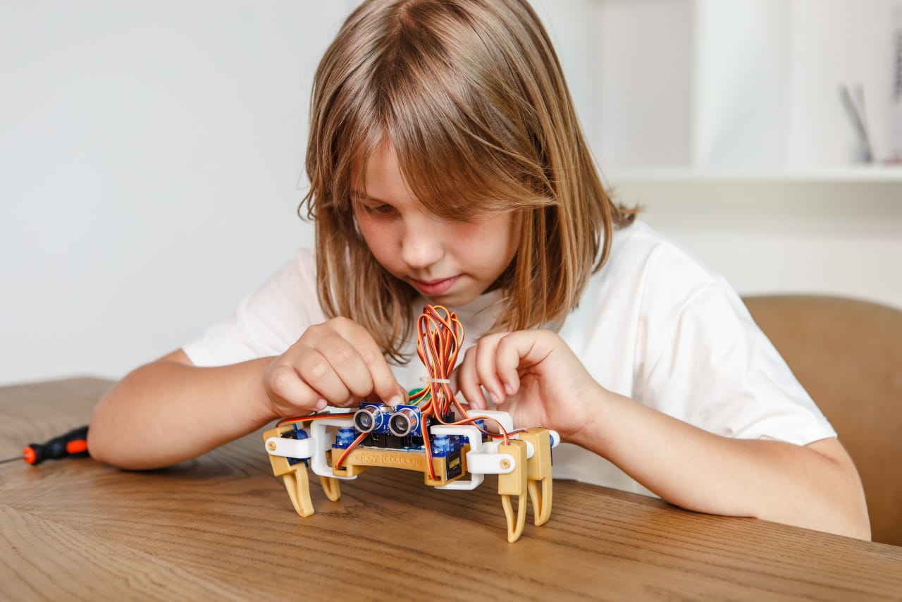 Ребенок собирает шагающего робота Enjoy Robotics