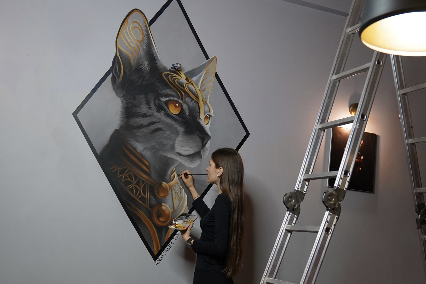 Девушка рисует кошку на стене