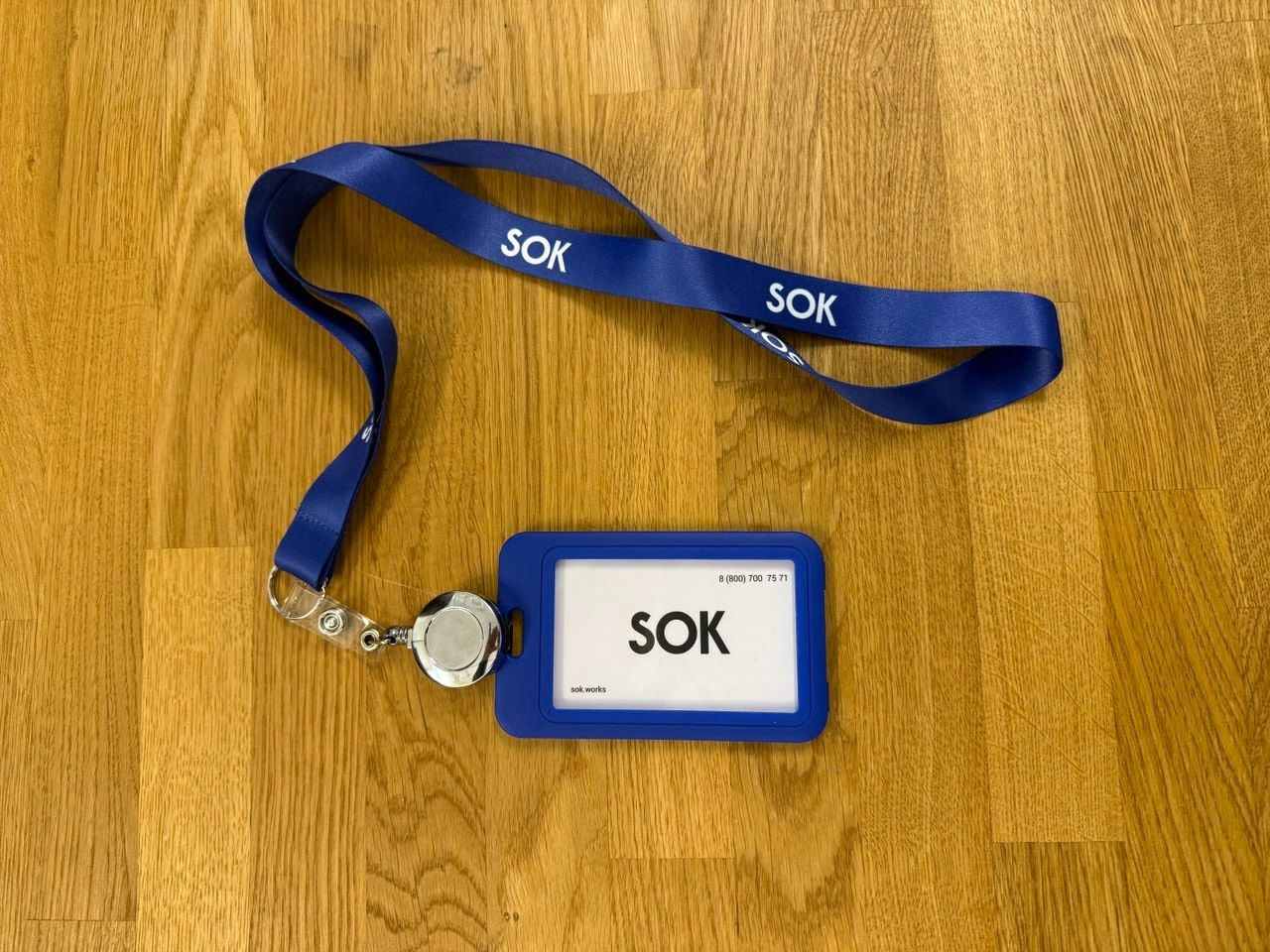 Корпоративный бейджик и лента SOK на деревянном столе