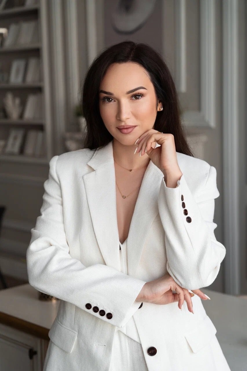 Девушка в белом пиджаке, рука у лица