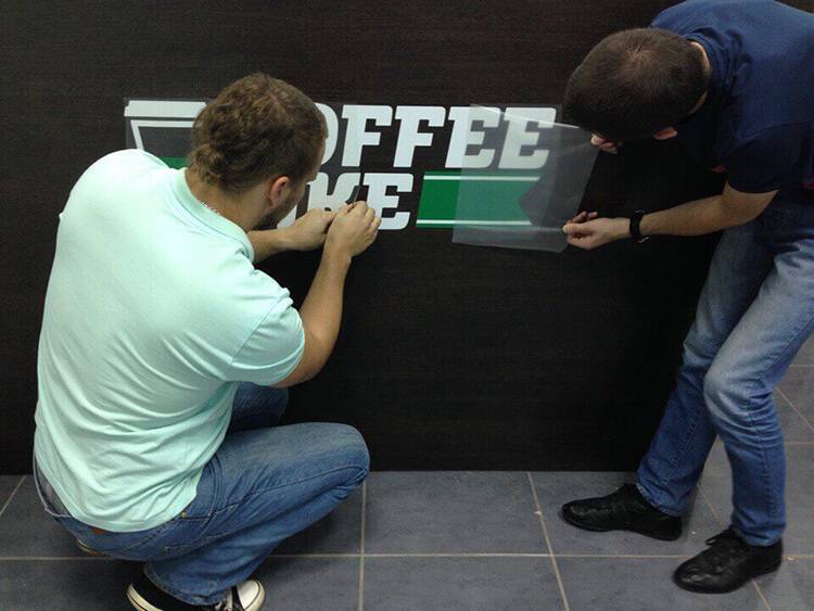 Никита с коллегой клеят логотип на первый кофе-бар