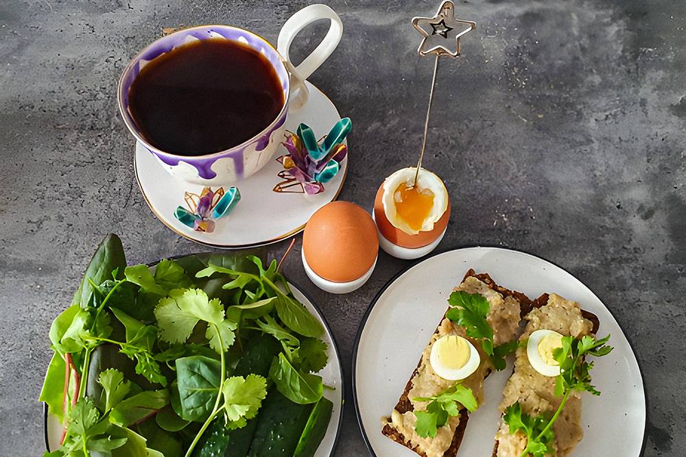 Завтрак: хлебцы с форшмаком, яйца всмятку, огурцы и тарелка зелени