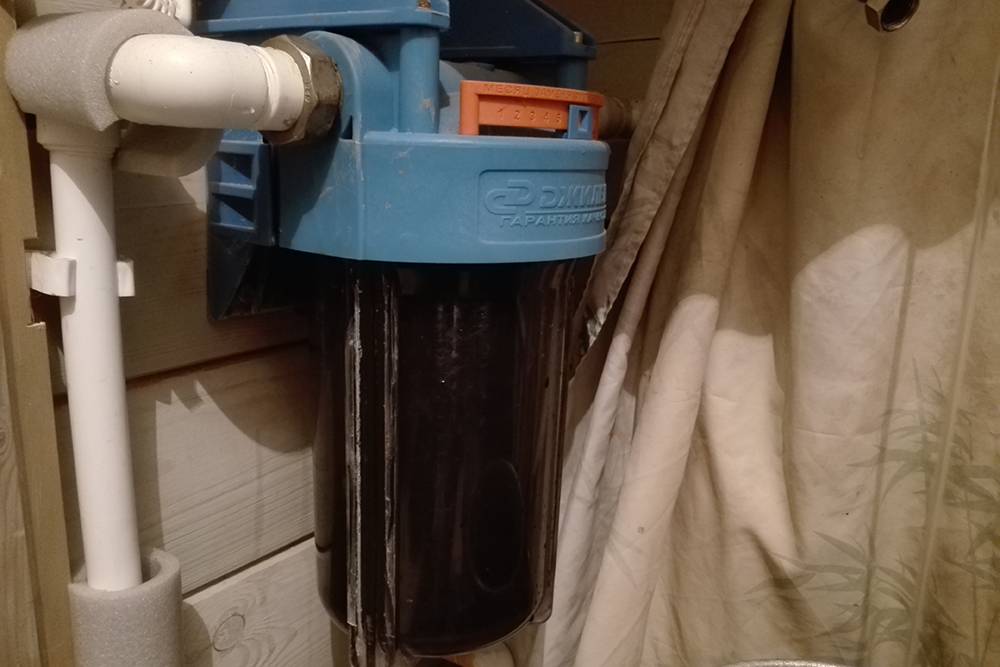 Когда я купил дом, воду из скважины очищал вот такой механический картриджный фильтр. Его колба прозрачная, но картриджа внутри уже не видно: все поглотила черная муть
