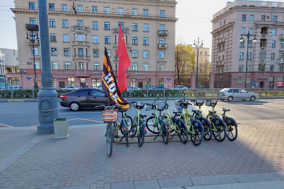 Велосипеды Smartbike у метро «Парк Победы». К парковке кто-то прицепил свой велосипед с флагами