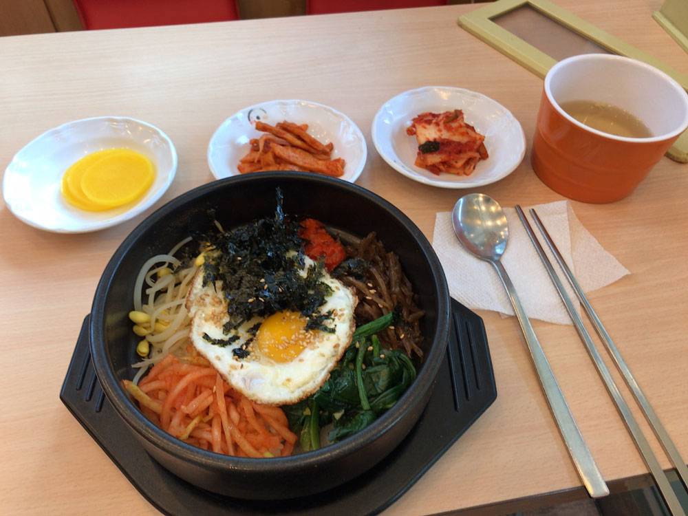 Традиционное корейское блюдо пибимпап. Обычно острый соус к нему подают отдельно, поэтому блюдо любят иностранцы, которые еще не привыкли к острой корейской еде. Стоит от 6000 ₩ (320 <span class=ruble>Р</span>)
