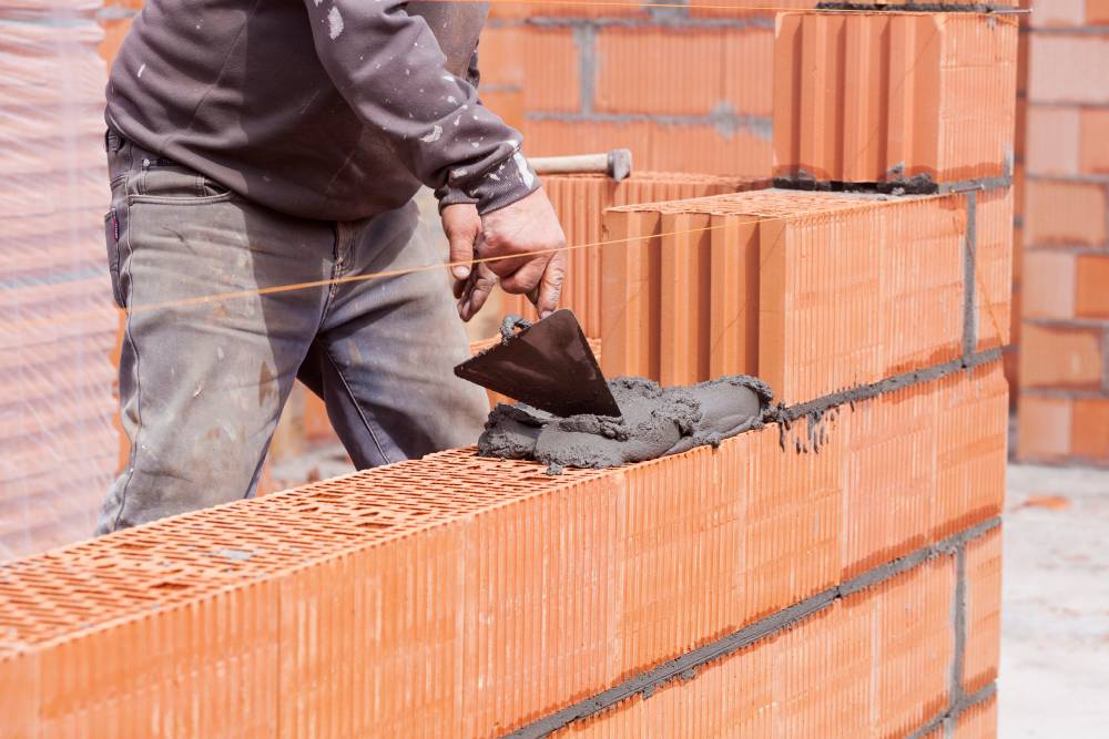 Процесс укладки керамических блоков. Они больше кирпича по размерам и за счет пористой структуры лучше сохраняют тепло. Источник: himki.brick360.ru