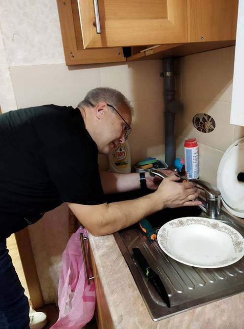 Социальный мастер из Вологодской области чинит кран в доме пожилого человека