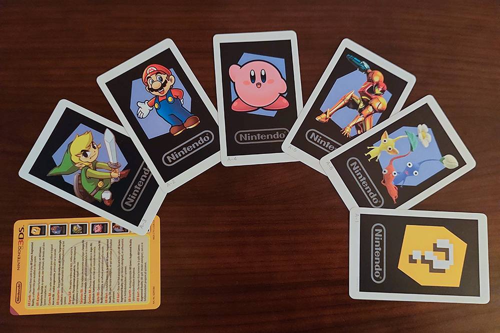 Аналог Amiibo — карточки дополненной реальности. Одни идут в комплекте с консолью, другие нужно покупать отдельно. Карточки на фото прилагались к моей New Nintendo 2DS XL