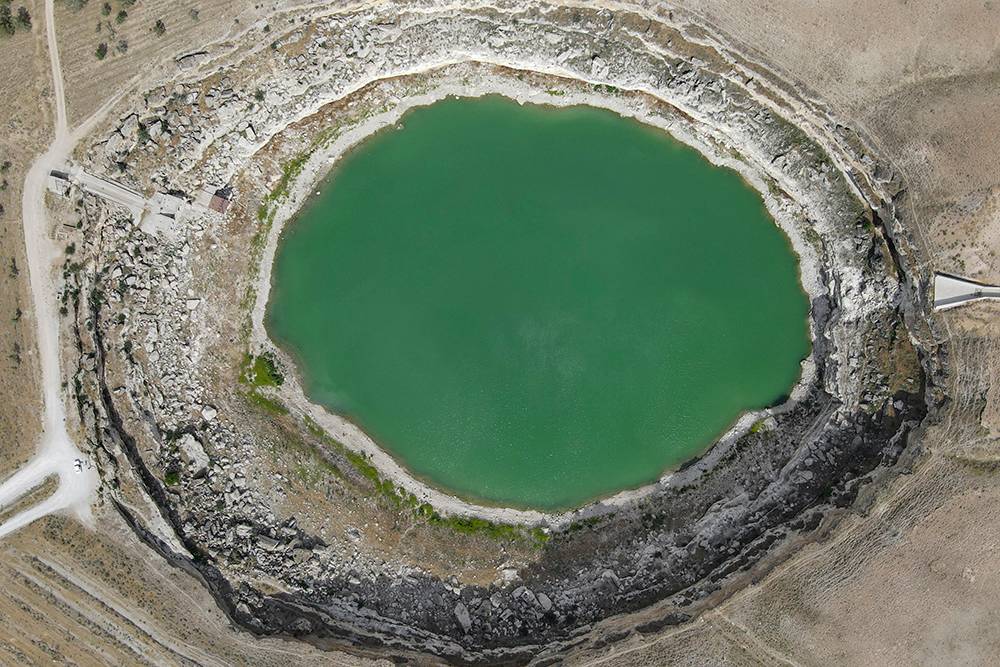 В этой воронке, заполненной водой, на свой страх и риск искупалась моя подруга, хотя у спуска были таблички, которые запрещали это делать. Насколько велик провал, можно понять по машине, которая припаркована на дороге в левой части кадра
