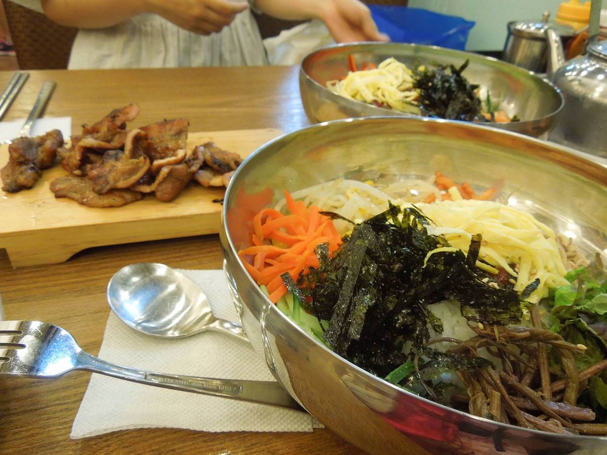 В глубокой тарелке рис с мясом и овощами — пибимпап, а на дощечке мясо, жаренное на гриле, — пулькоги