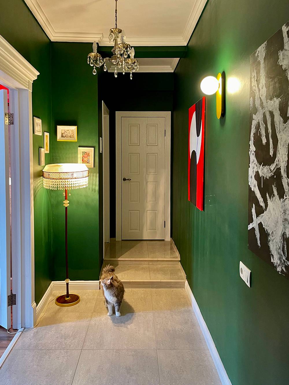 В коридоре зеленые стены, картины и хрустальная люстра