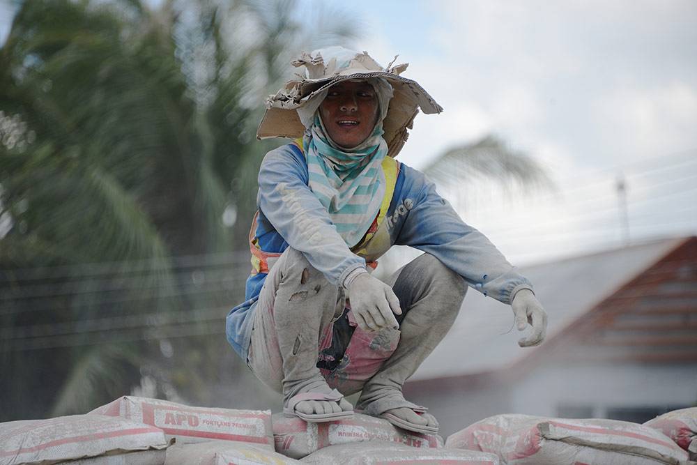 Грузчик на мешках цемента в городе Давао