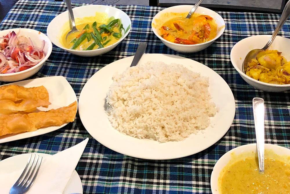 Традиционный шри-ланкийский карри. В тарелках слева направо — пападам, лук с помидорами, стручковая фасоль с карри, креветки с карри, жареная картошка, горох в карри