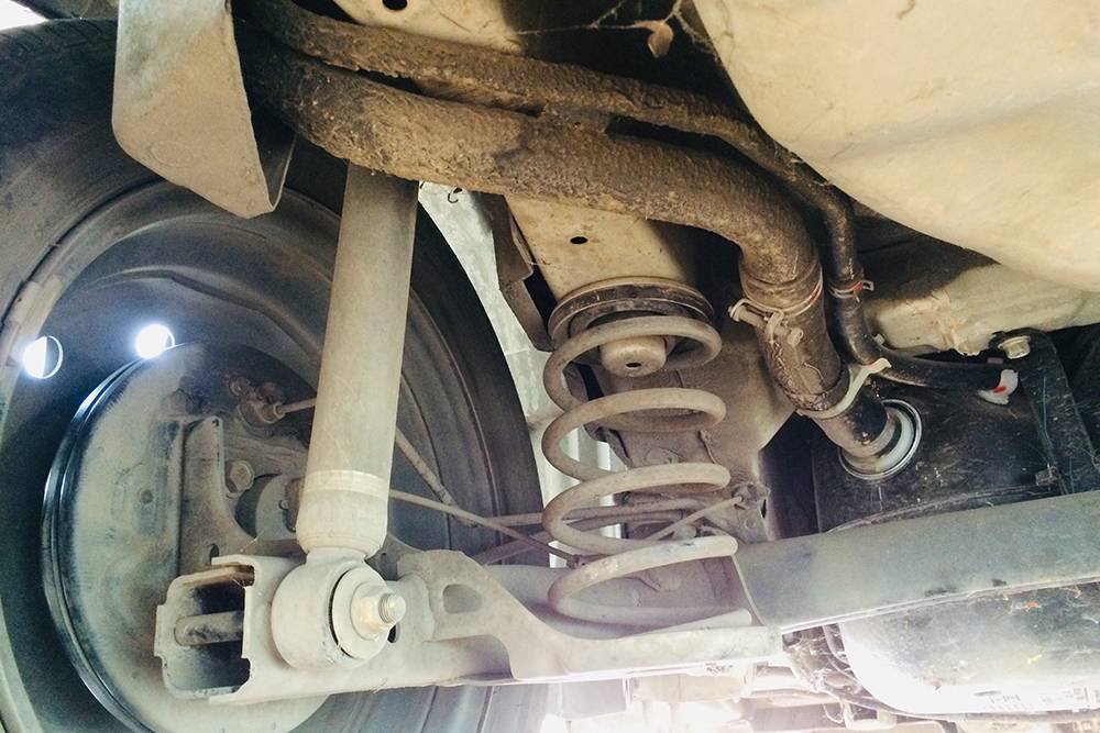 Зависимая задняя подвеска переднеприводного автомобиля. Кажется, что она ржавая и покрыта большим слоем грязи. Но это не всегда означает, что ее нужно полностью менять. Фото: Boot Worrarong / Shutterstock