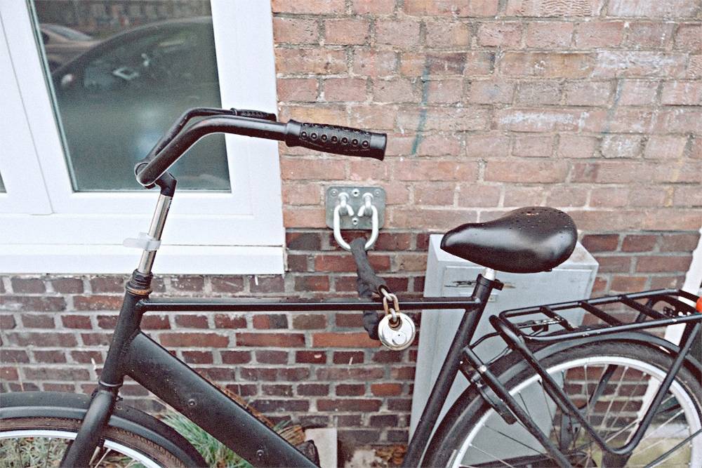 Так паркуют велосипеды в Амстердаме. Владелец прицепил велосипед к крюку в стене и заблокировал заднее колесо, чтобы нельзя было уехать. Два замка надежнее, чем один, но переднее колесо все еще могут украсть
