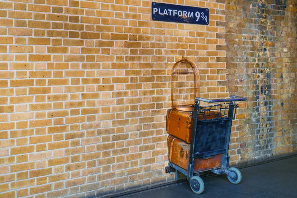 Табличка и тележка, будто бы наполовину прошедшая сквозь стену, напоминают, что платформа 9 3/4 находится на вокзале Кингс-Кросс. Фото: NoyanYalcin / Shutterstock