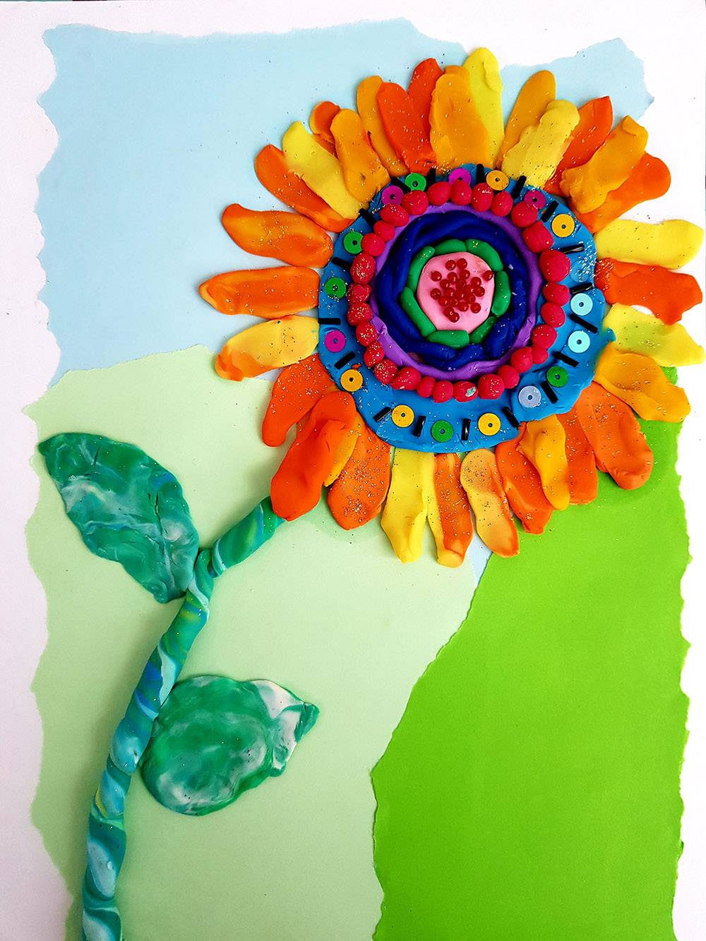 Подсолнух по уроку пластилиновой живописи в онлайн-лагере. Фон сделан в технике рваной аппликации, цветок украшен бисером и пайетками, в пластилин вкатаны мелкие блестки. Детали делают работу интереснее и фактурнее