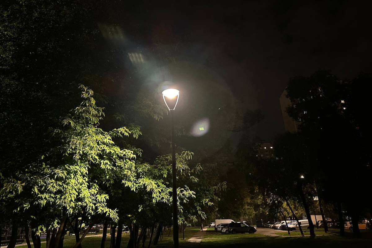 Сложная ночная сцена: яркий фонарь проработан достаточно четко, а на фоне в темноте хорошо видно дерево слева и дом справа. Парковка на заднем плане не пересвечена