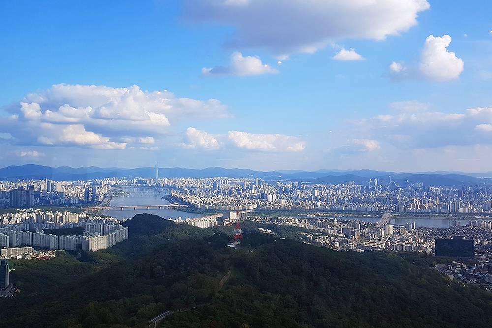 Панорама Сеула со смотровой площадки. Вдалеке виднеется огромный небоскреб World Lotte Tower