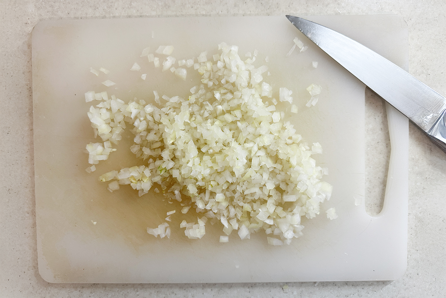 Шаг 1. Лук и чеснок мелко порубите. Бульон разогрейте в сотейнике или микроволновке либо залейте бульонный кубик 200 мл кипятка по инструкции на упаковке