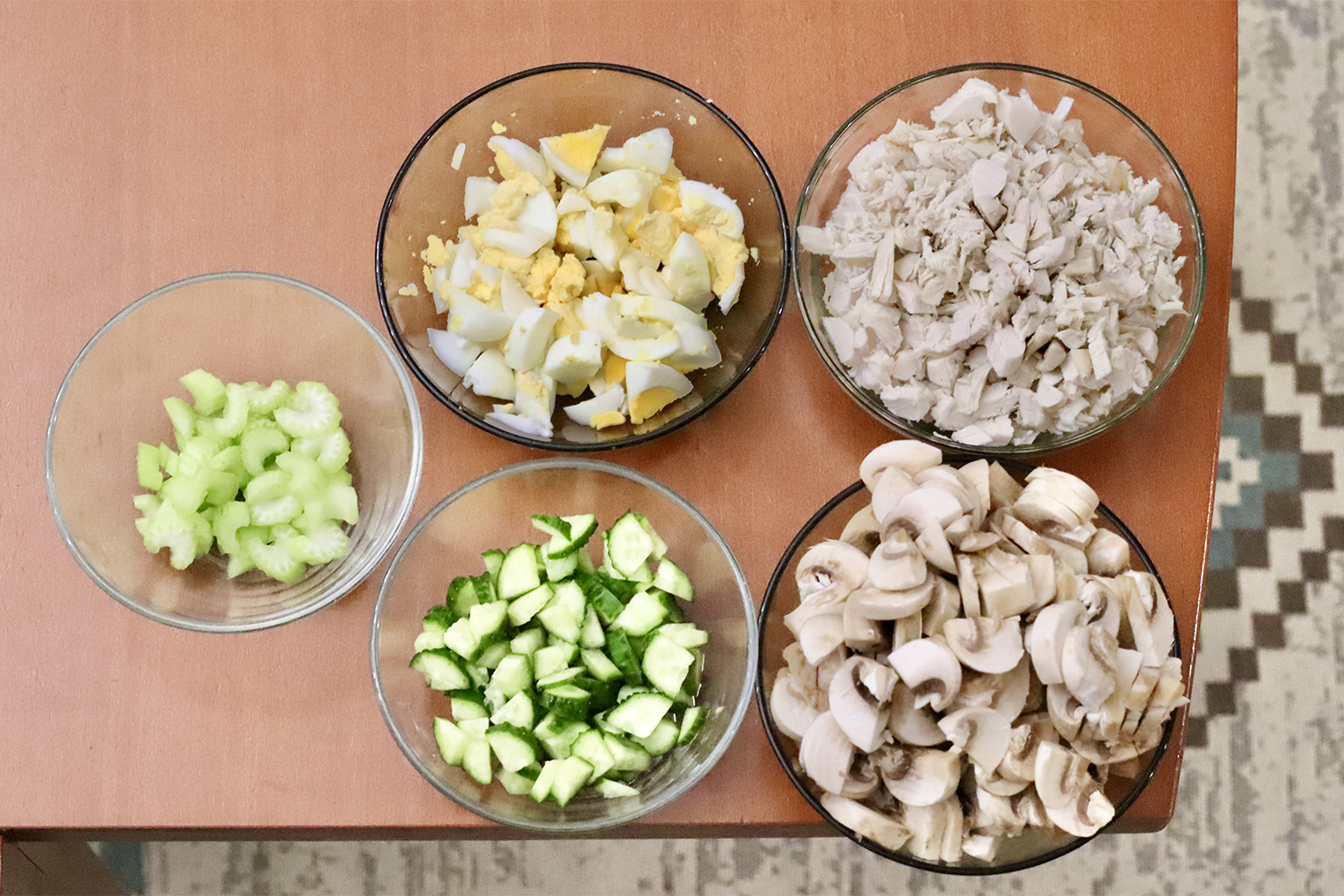 Шаг 1. Яйца отварите вкрутую — 10 минут после закипания воды. Остудите в холодной воде, очистите. Яйца, курицу, шампиньоны, сельдерей и огурец нарежьте одинаковыми кусочками