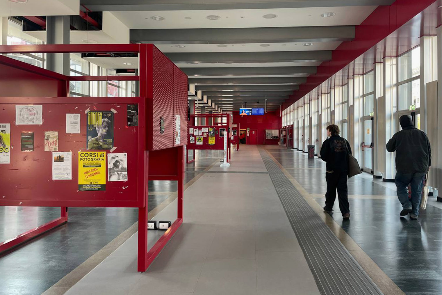 Факультет гуманитарных наук Туринского университета. Стены красные в цвет герба вуза. На стендах можно найти объявления о курсах, выставках, съеме жилья и о психологической помощи