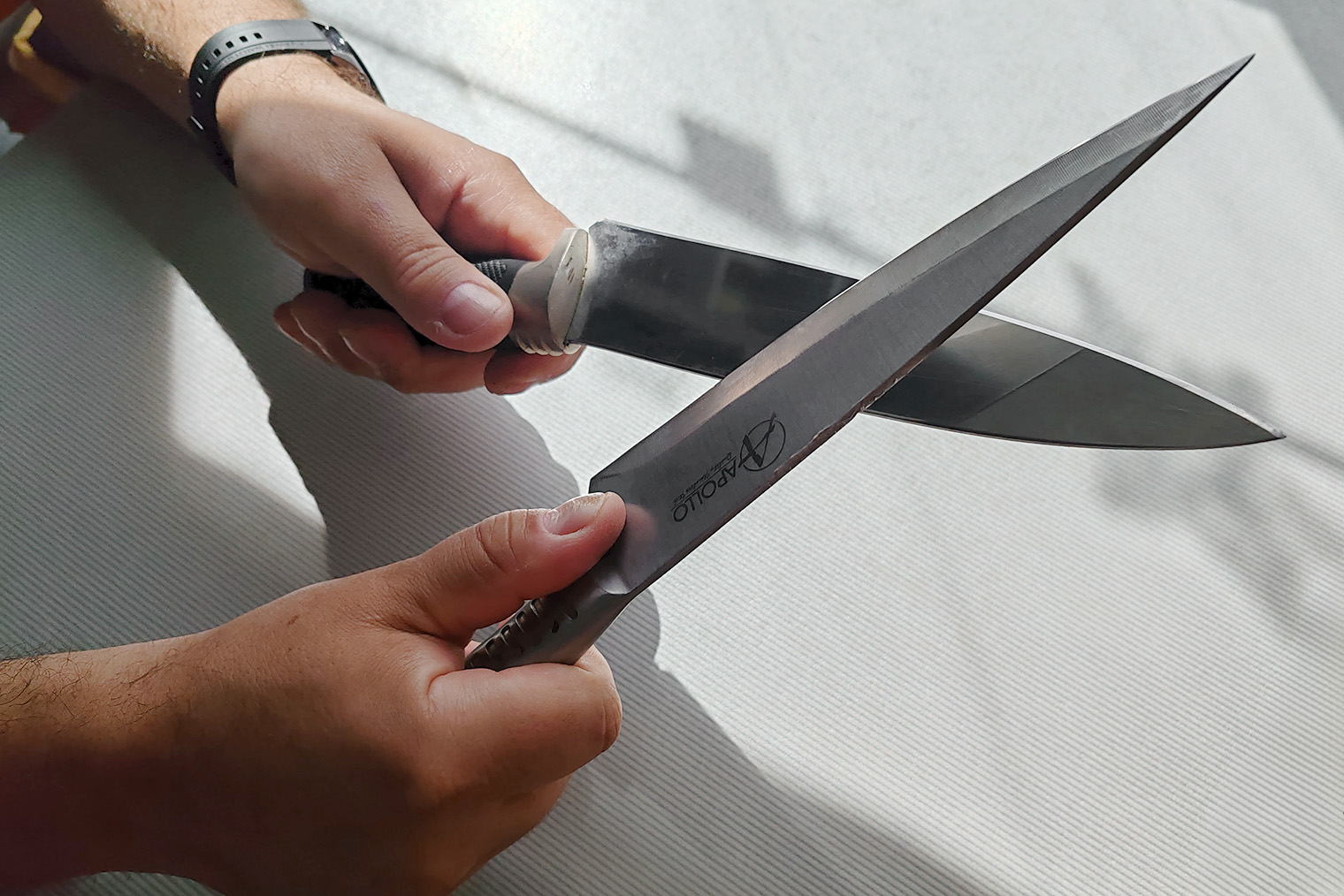 Ведите лезвие ножа на себя по обуху второго ножа. Обух — это верхняя незаточенная часть клинка