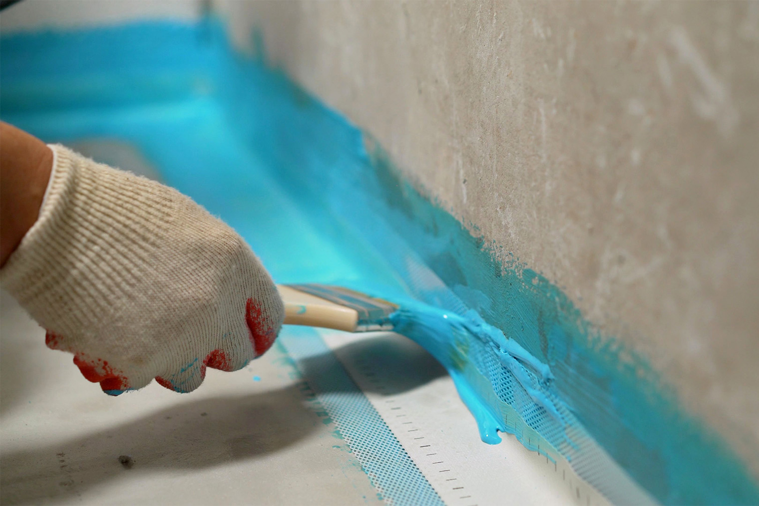 Вдоль стыка пола и стены клеят гидроизоляционную ленту, а сверху тщательно промазывают мастикой. Фотография: Sidorov_Ruslan / Shutterstock