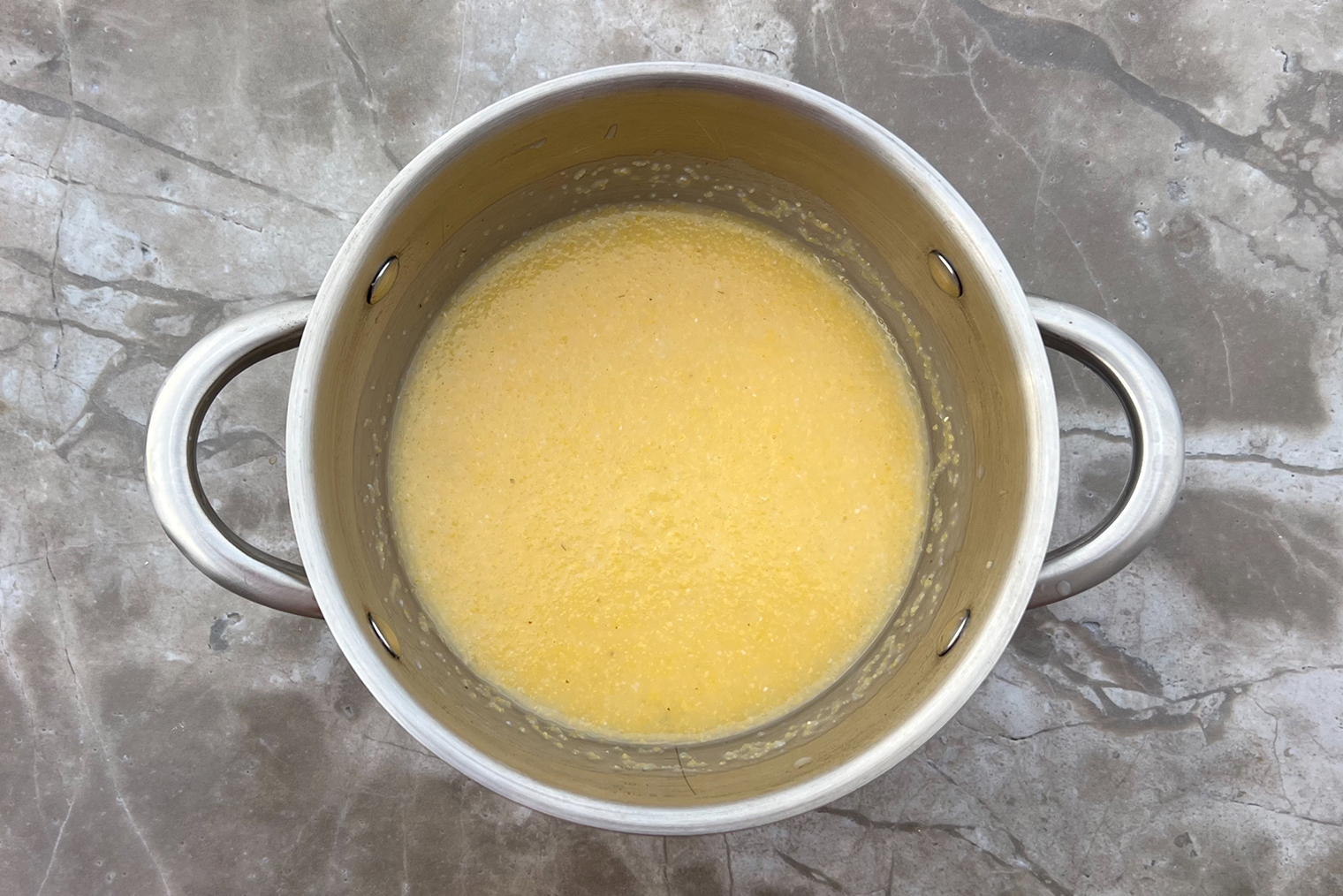 Шаг 2. Поленту варите до мягкости столько, сколько рекомендует производитель, постоянно помешивая, чтобы крупа не пригорела. У меня на это ушло около 35 минут. Если каша начнет густеть, добавьте немного воды или бульона — я подлила около 150 мл жидкости. Готовую кашу посолите и перемешайте. На этом этапе можно добавить 50—100 мл сливок или пару ложек сливочного масла, чтобы сделать блюдо насыщеннее. После этого проварите поленту еще 2—3 минуты и снимите с огня