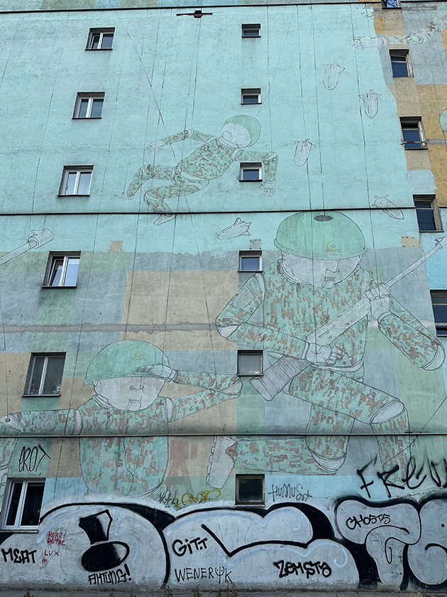 Мне очень нравится это граффити, хоть оно и старое. Солдаты-марионетки десантируются вместе с бомбами. На плечах — знак доллара, на касках — евро, переделанный под советский серп. У поляков тоже есть мем про евросовок!
