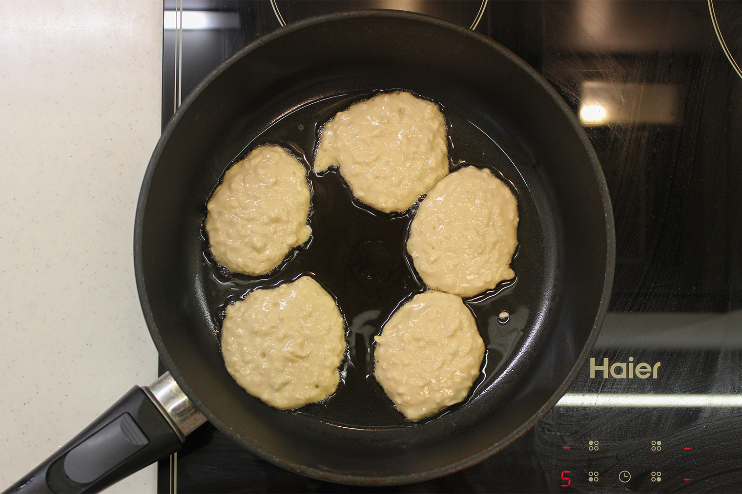 Шаг 3. Разогрейте сковороду на среднем огне, смажьте растительным маслом. Выложите по 1 ст. л. теста на сковороду так, чтобы между будущими оладьями осталось немного места и они не слиплись