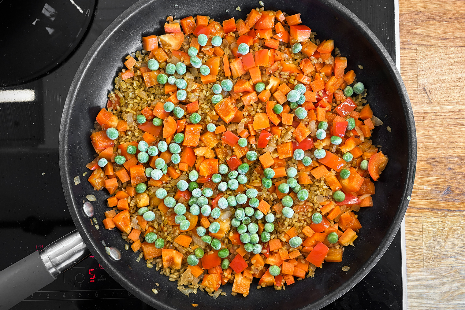 Шаг 3. Булгур добавьте в сковороду к овощам и обжаривайте 2 минуты, помешивая. Всыпьте зеленый горошек