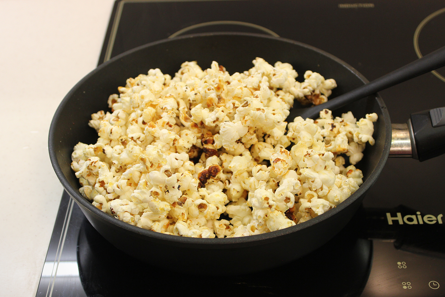 Шаг 3. Когда хлопки станут реже, выключите плиту. Снимите крышку и тщательно перемешайте попкорн, чтобы распределить карамель. Могут раскрыться не все зерна — это нормально