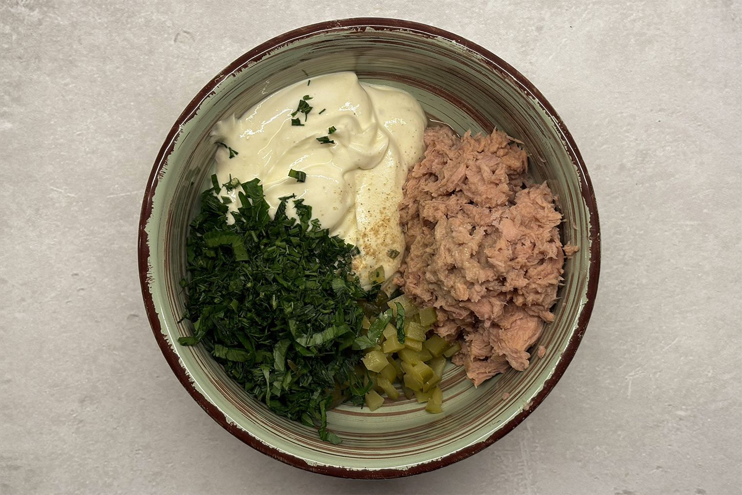 Шаг 3. Из консервированного тунца слейте жидкость. Рыбу переложите к творожной массе и разомните вилкой. Добавьте лимонный сок, огурцы и зелень, посолите и перемешайте