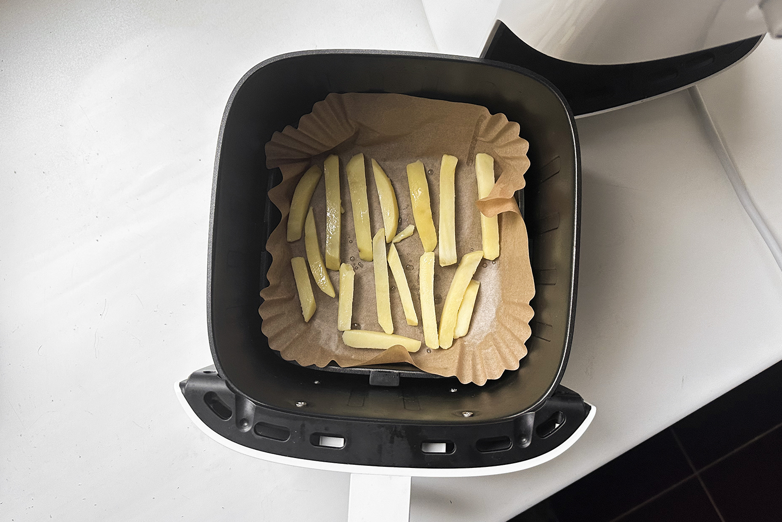 Шаг 4. Выложите брусочки в чашу аэрогриля так, чтобы между ними оставалось пространство. Сделайте пару пшиков подсолнечного масла из дозатора или добавьте половину чайной ложки масла. Поставьте чашу в гаджет и готовьте картошку при 165 °C 15 минут. После того как картошка обжарилась, опять охладите ее в холодильнике 20—30 минут
