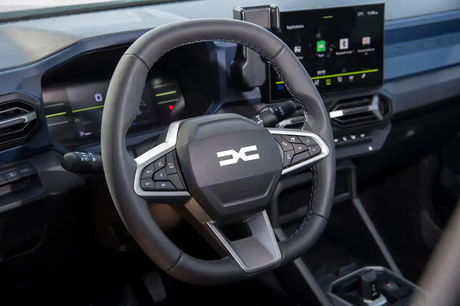 Экран на центральной консоли немного развернут в сторону водителя, а Y⁠-⁠образные воздуховоды напоминают элементы нового логотипа Dacia. Эту же форму можно увидеть в подлокотниках дверей, ДХО и задних фонарях. Источник: Dacia