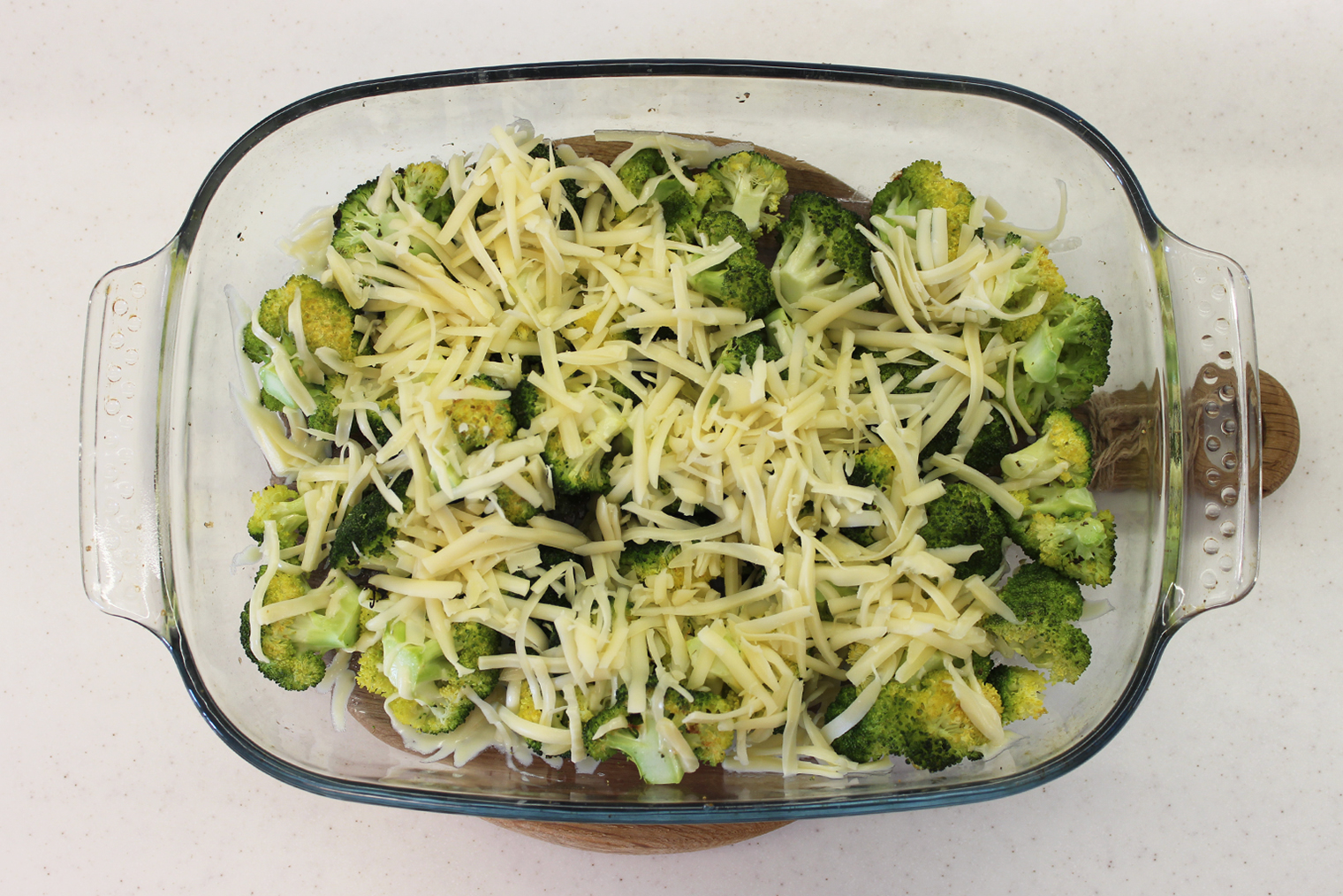 Шаг 4. Брокколи достаньте из духовки. Температуру убавьте до 100 °С. Капусту посыпьте сыром и запекайте еще 15 минут, пока он не расплавится