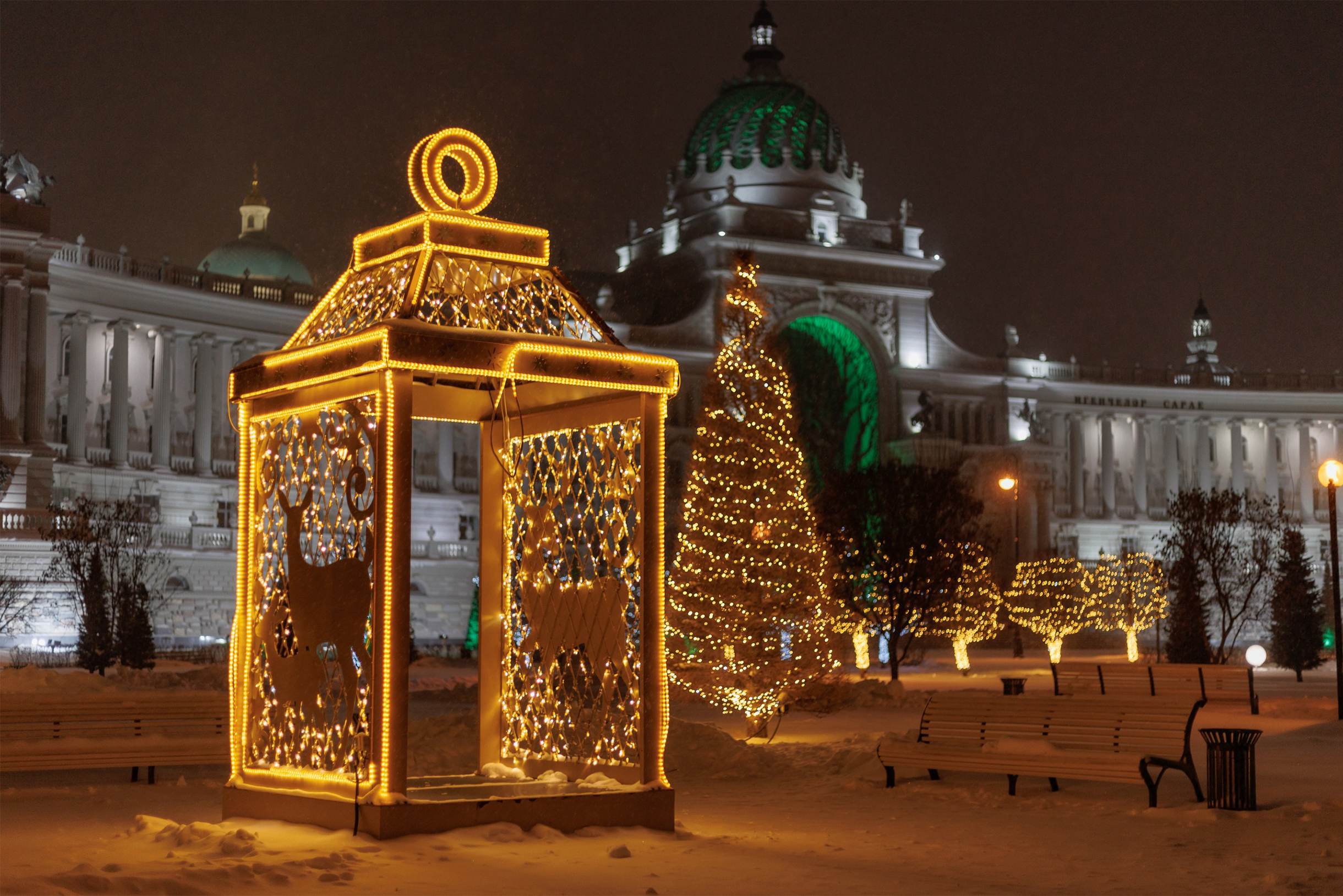 Деревья украсили гирляндами. Рядом — елочная игрушка в форме фонарика со сквозным проходом