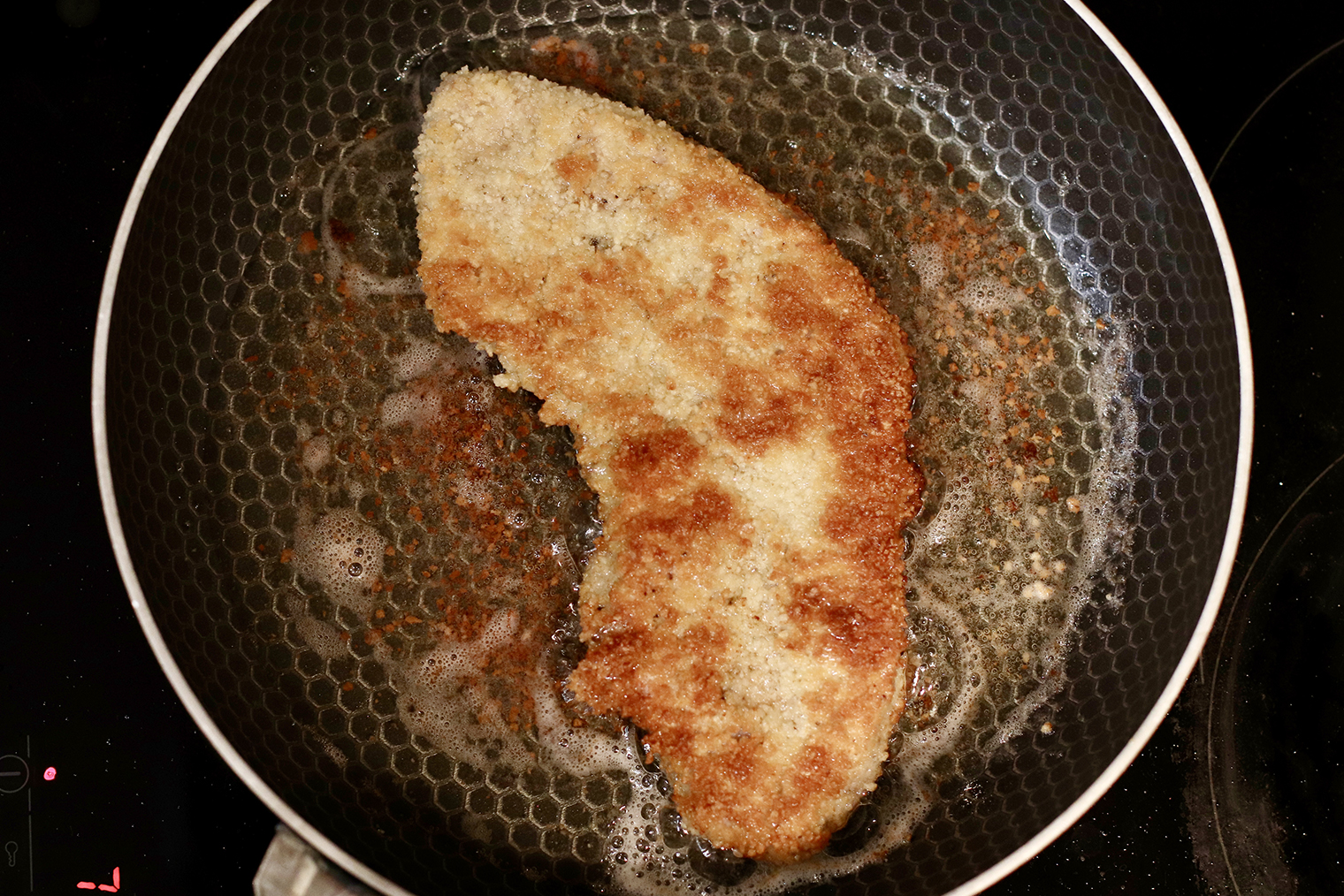 Шаг 5. Сковороду поставьте на огонь выше среднего, масло разогрейте. Чтобы проверить его готовность, бросьте в жир щепотку сухарей — вокруг них должны появиться пузыри. Шницели обжаривайте по 1 минуте с каждой стороны до золотистой корочки, убавьте жар до среднего и готовьте еще по 2 минуты с двух сторон